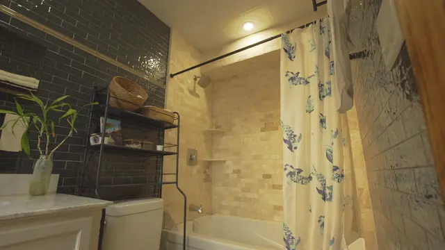 The bathroom vanity — green tile, brass taps and plants