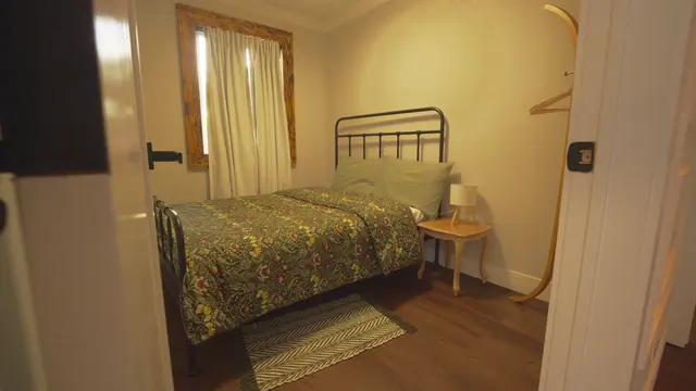 A bedroom with a patterned bedspread and a wood-framed window