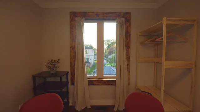 A bedroom with a window and red chairs